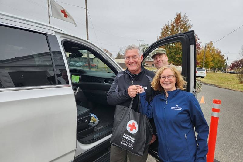 Red Cross SAF load turkey and bag of side dish makings in service member car on JBMDL during Operation Turkey