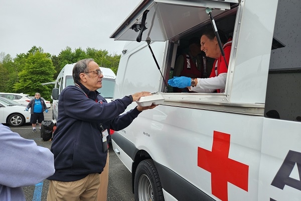 red cross volunteer serving food to client 