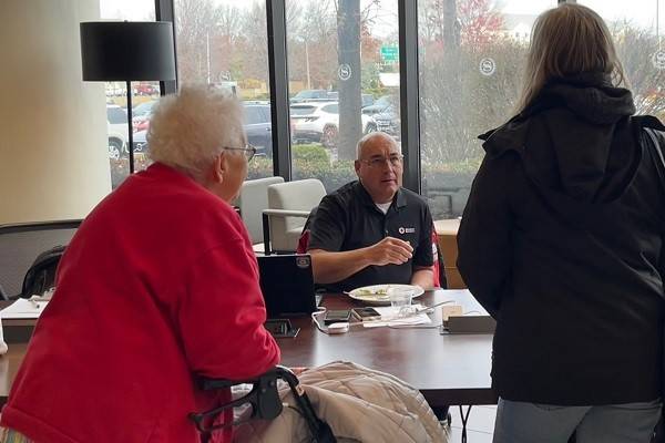 Red Cross worker speaking with people in an office.
