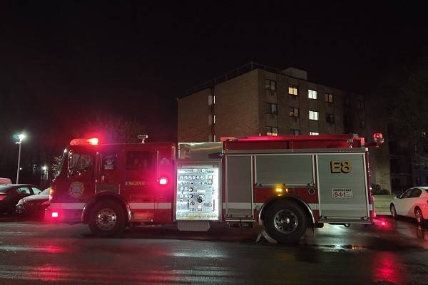 Fire truck on street at night with lights on.