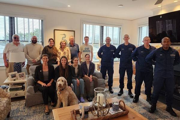 group of U.S. coast guards and a family in a home pose for picture.