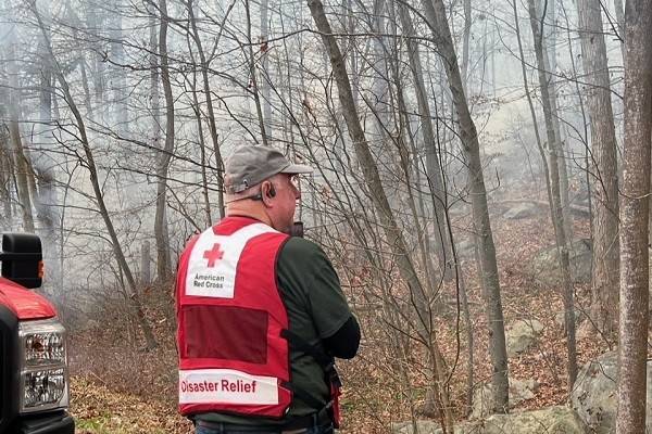 Red Cross volunteer wearing hat and red cross vest in a forest.