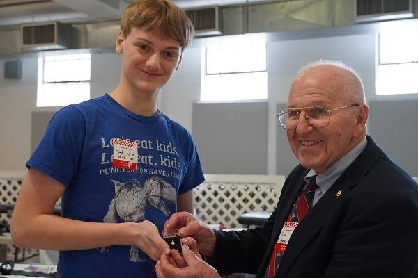 Volunteer John Burns presents pin to donor at blood drive