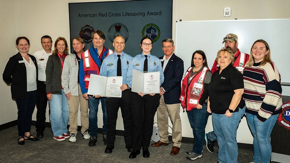 AJ Gonzales and Makayla Bowers, with a group of Red Crossers, hold their Red Cross lifesaving awards.