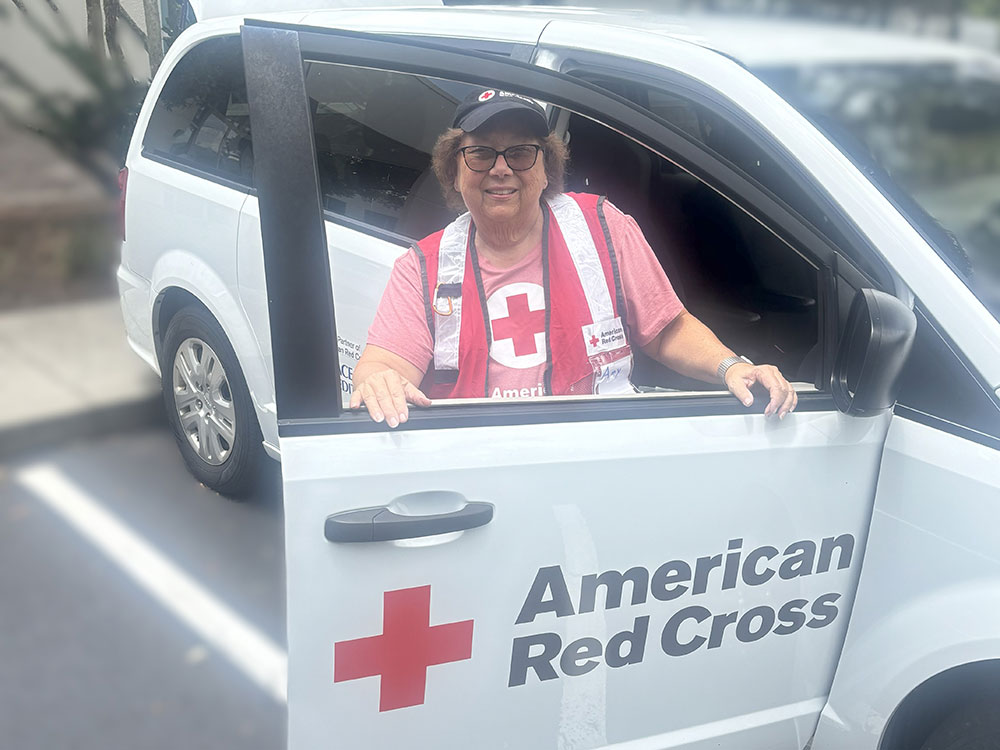 Red Cross volunteer next to Red Cross van with the door open.