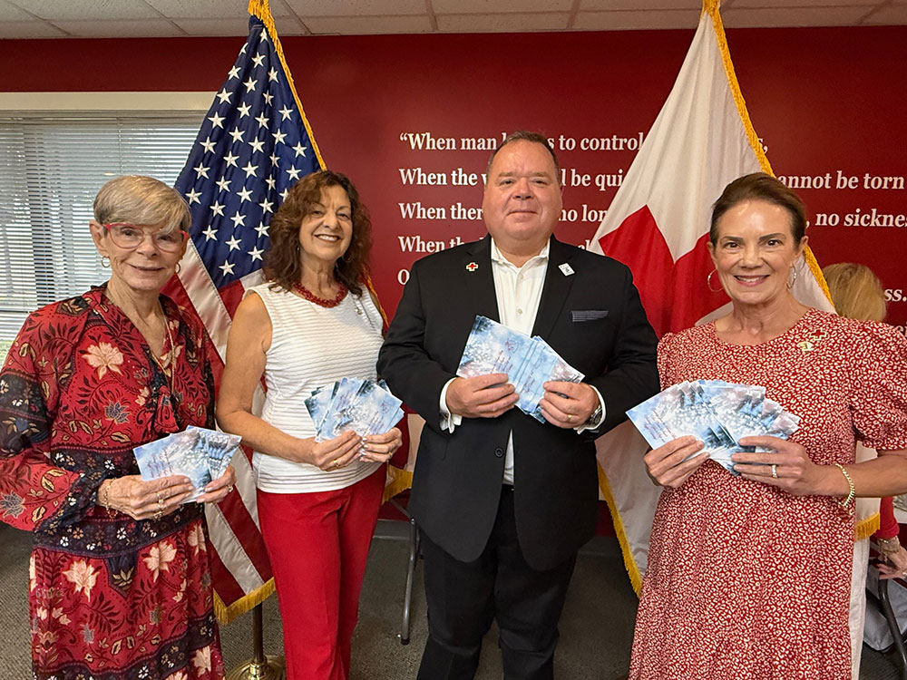 four Red Cross staff members holding cards and smiling for picture.
