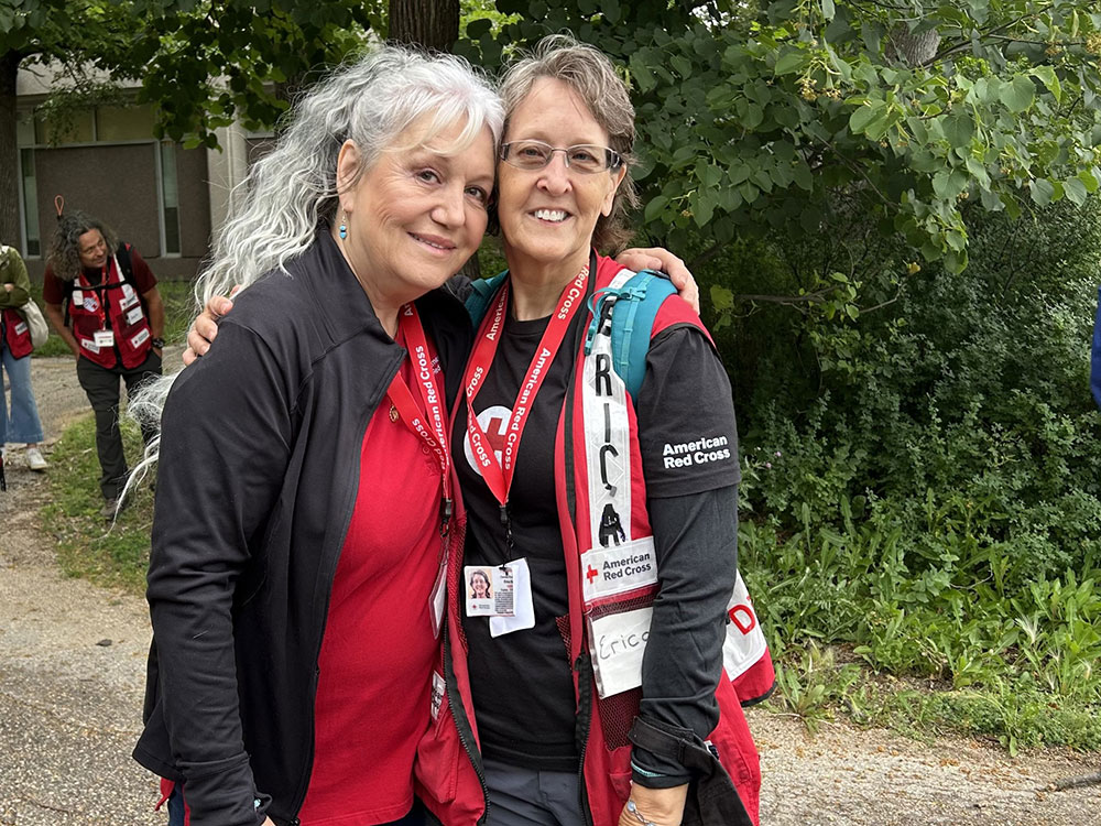 two Red Cross volunteers pose for picture with each other.