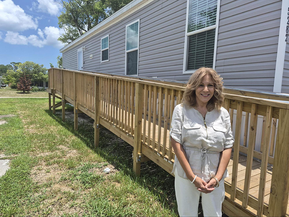 Isabel Guzman smiling while standing next to a wooden ramp next to a house.
