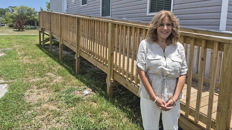 Isabel Guzman smiling while standing next to a wooden ramp next to a house.
