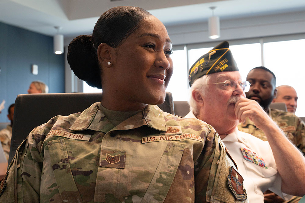 Keosha Middleton, wearing military clothes, sitting down in room with other military members.