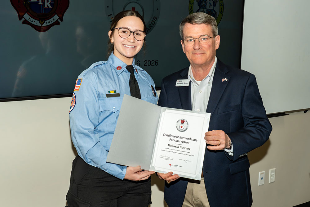 Makayla Bowers holding a lifesaving award while standing next to Mike Brown, executive director of the Tampa Bay area for the American Red Cross.