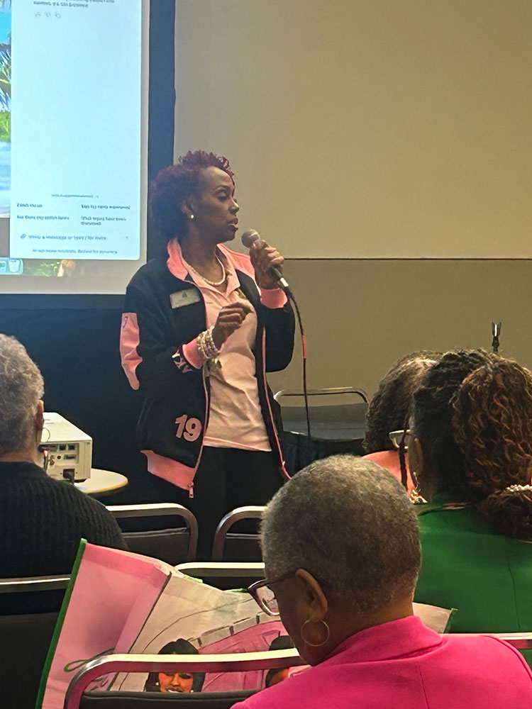 Dr. Andrea Pullen speaking on a mic to a room full of people.