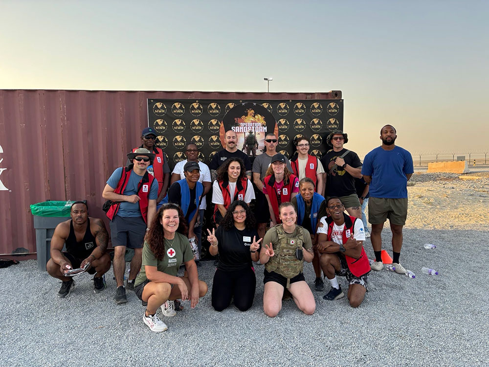 Red Cross volunteers and military members group photo at the beach.