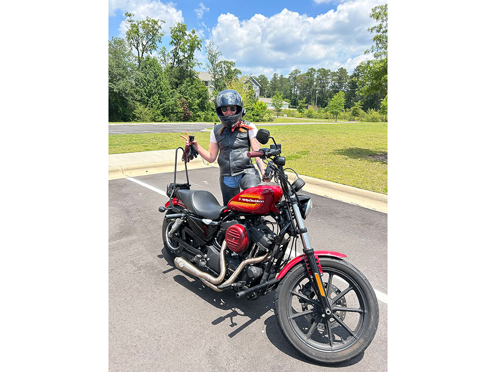 Angelica Sowynn standing next to a motorcycle and wearing a helmet.