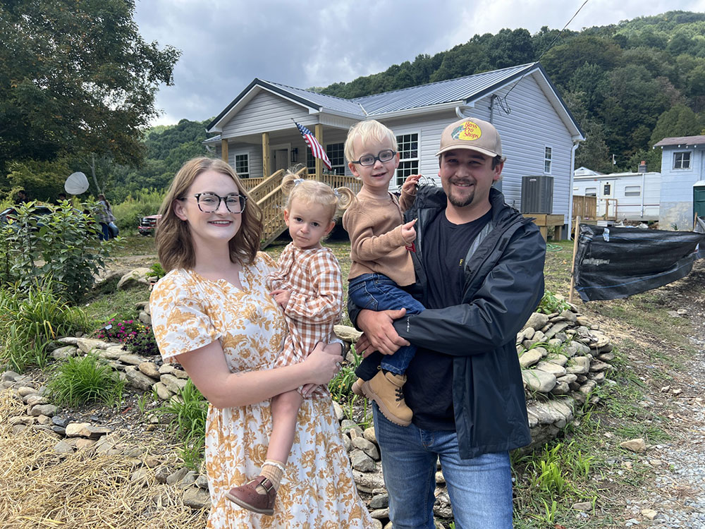 Brianna Brown and her husband holding their twin toddlers outside their home.