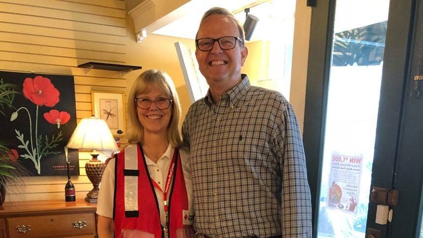 Red Cross volunteer Daryl Steinbraker standing next to a man and smiling for picture.