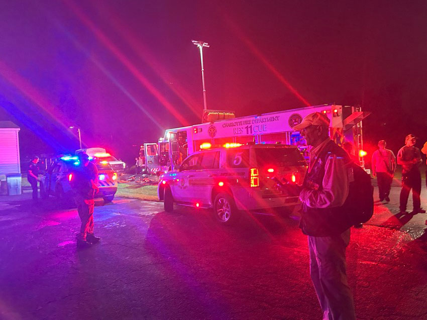 Johnny Anderson at night standing next emergency vehicles and emergency staff members with their lights on in the street.
