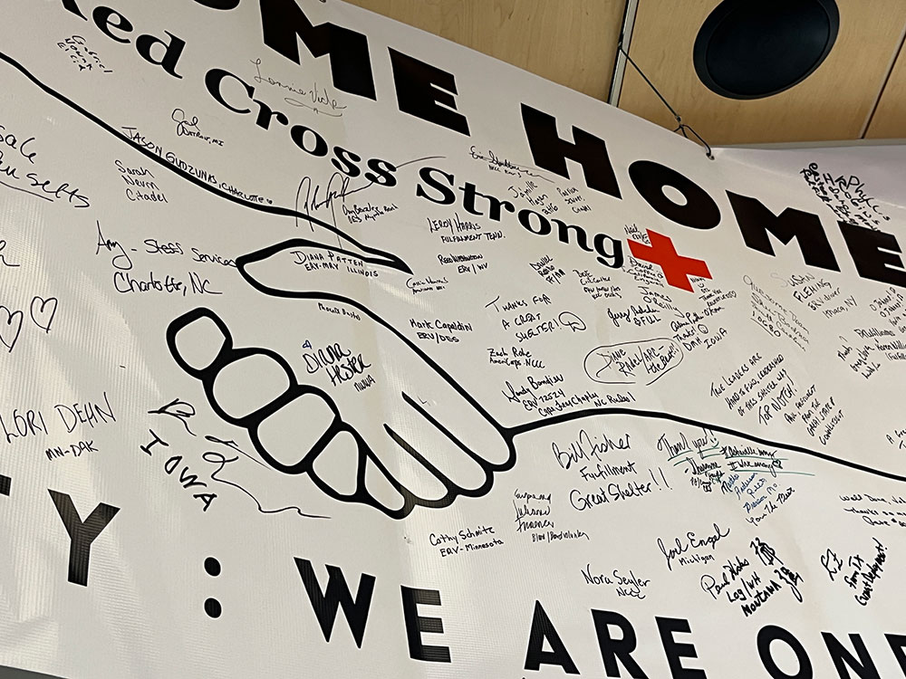 Close up pic of Welcome home banner with drawing of two hands shaking and hand written signatures all over the banner.