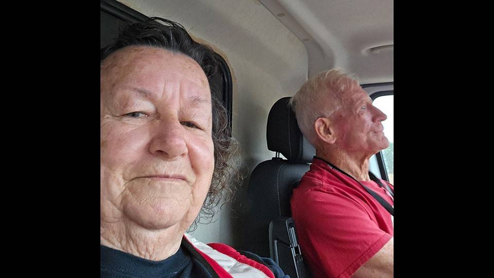 Red Cross volunteer Helen Miller takes a selfie in her emergency response vehicle with another volunteer in the driver's seat.