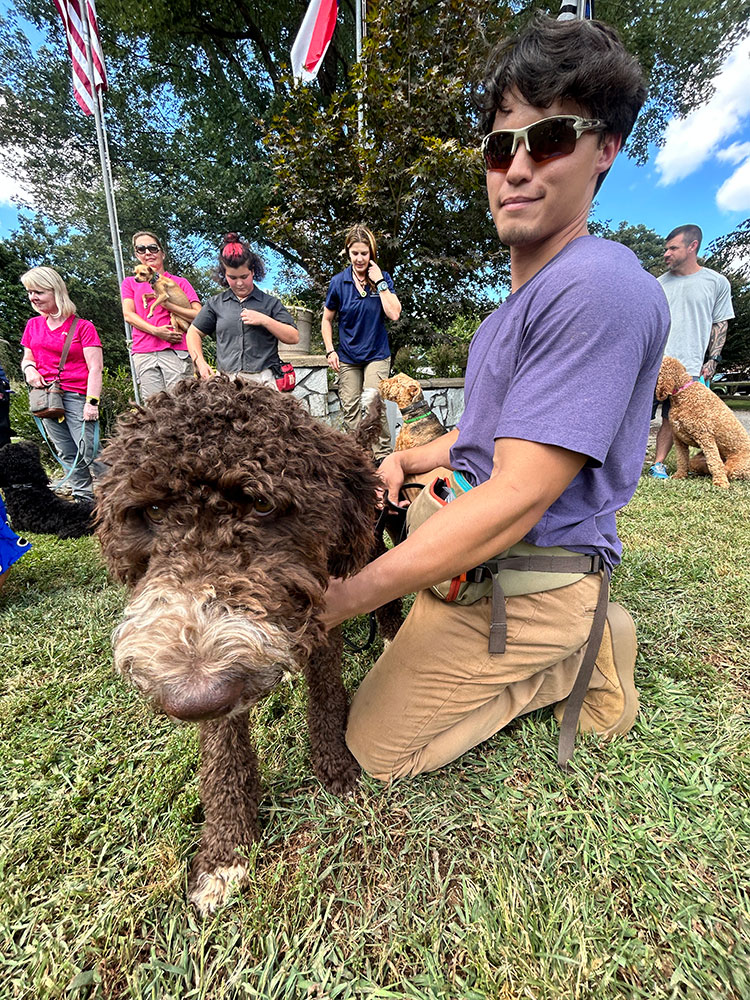 Highland Canine staff with pups on a grassy field.