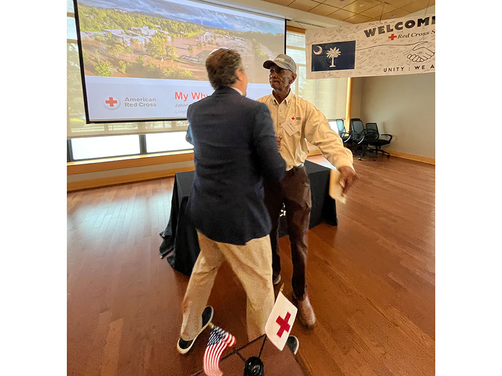 Johnny Anderson walking towards and about to hug a Red Cross staff member.