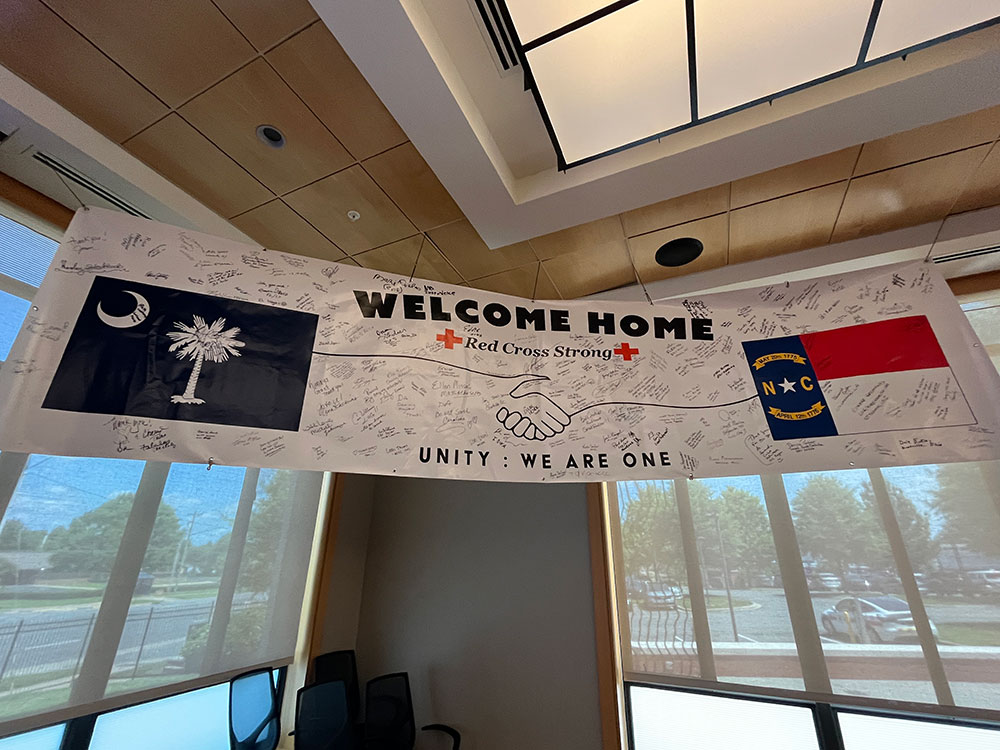 Welcome home banner with drawing of two hands shaking and hand written signatures all over the banner.