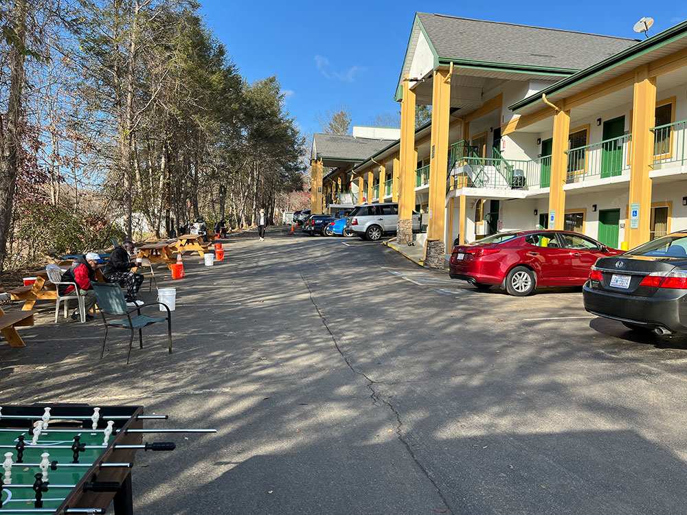 Intermediate housing complex with people and different items in the parking lot.