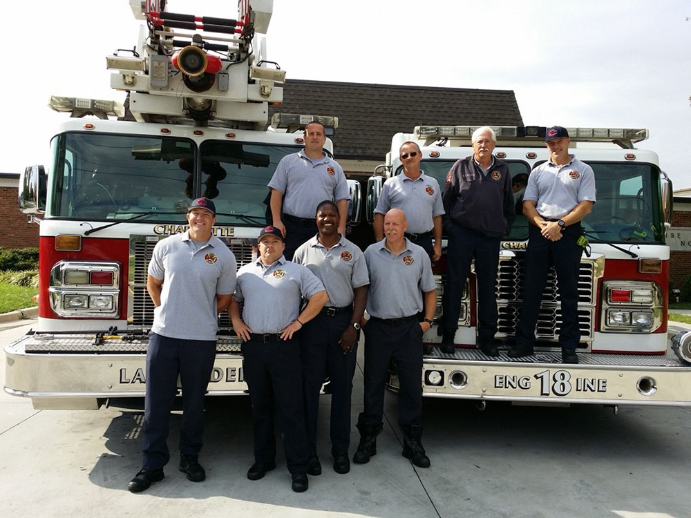 Retired Charlotte firefighter and U.S. Marine Corps veteran Frankie Knox with his Charlotte Fire team standing in front of two fire engines.