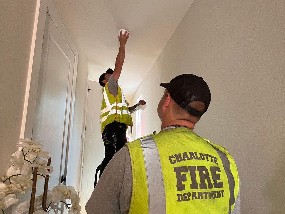 Charlotte firefighters install a free smoke alarm on a ceiling.