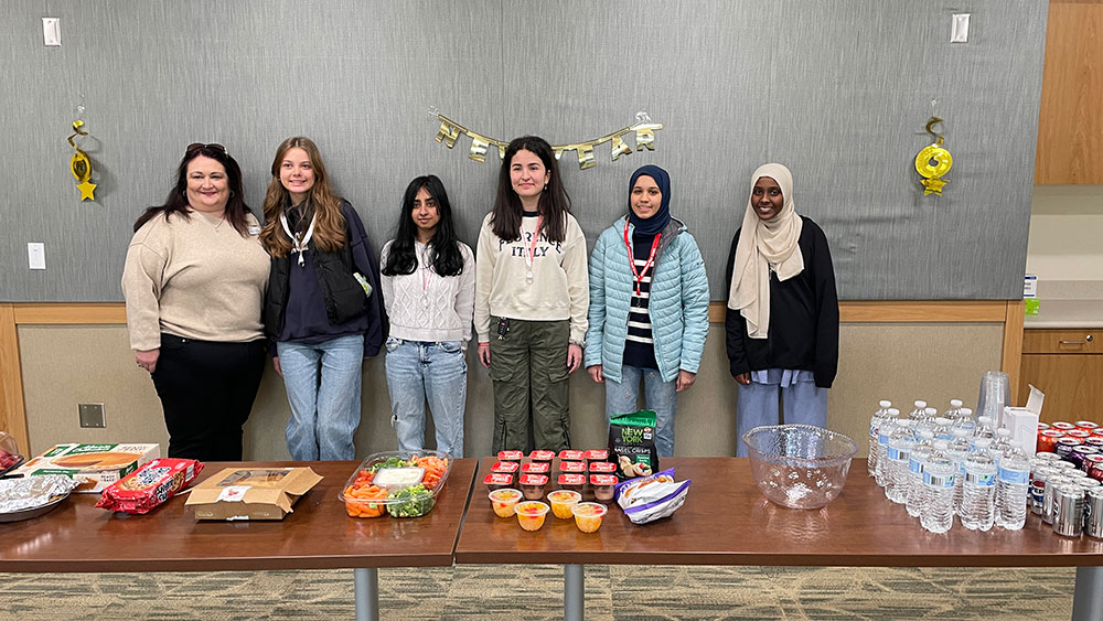 Group photo of Red Cross HS Club members standing next to tables with healthy snacks and bottled water.