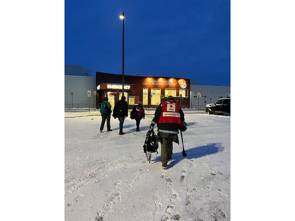 Red Cross volunteers walking through the snow towards a hospital.