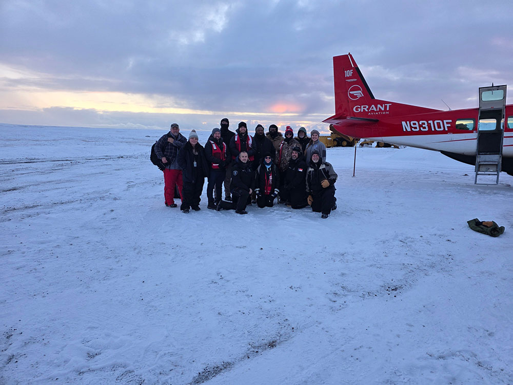 Group of Red Cross volunteers in the snow next to an airplane.
