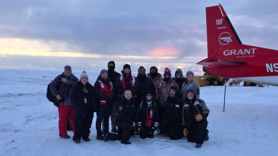 Group of Red Cross volunteers in the snow next to an airplane.