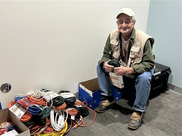 Person sitting in a room next to a pile of new extension cords.