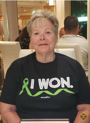 Sherry Kemp smiling, wearing a black "I Won" T-shirt with a green awareness ribbon.