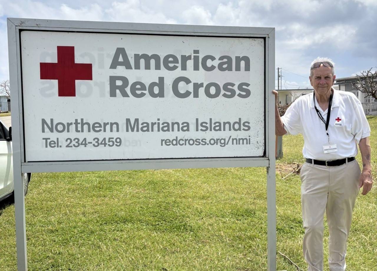 Steady Meres stands in front of a Red Cross sign in Saipan