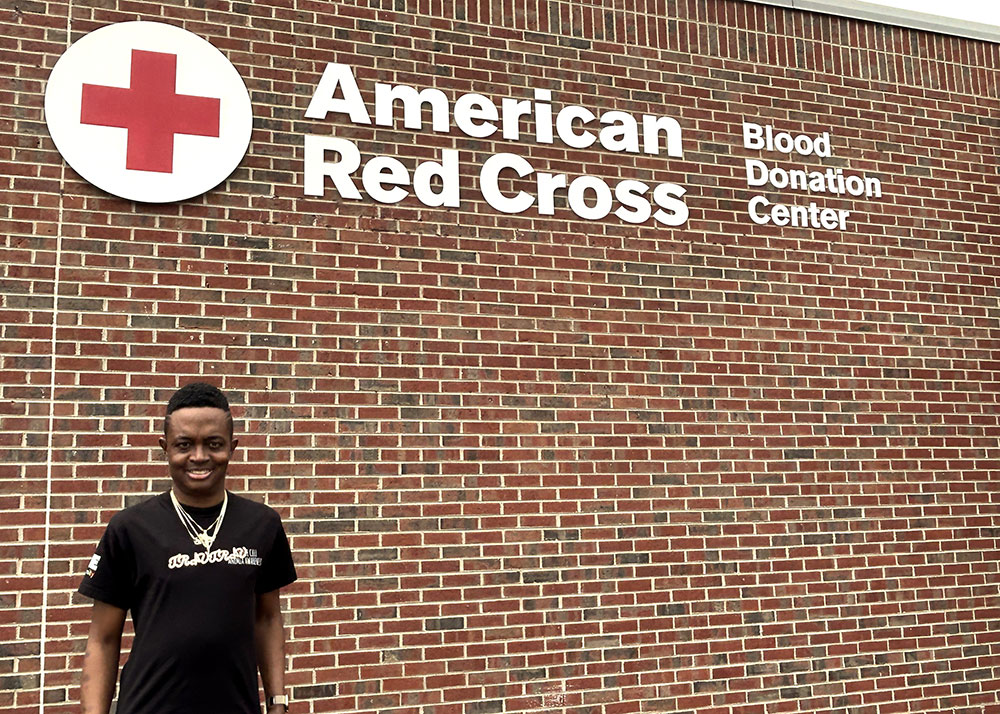 Travis Robinson standing next to an American Red Cross blood donation center building.