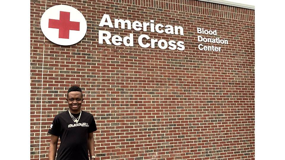 Travis Robinson standing next to an American Red Cross blood donation center building.