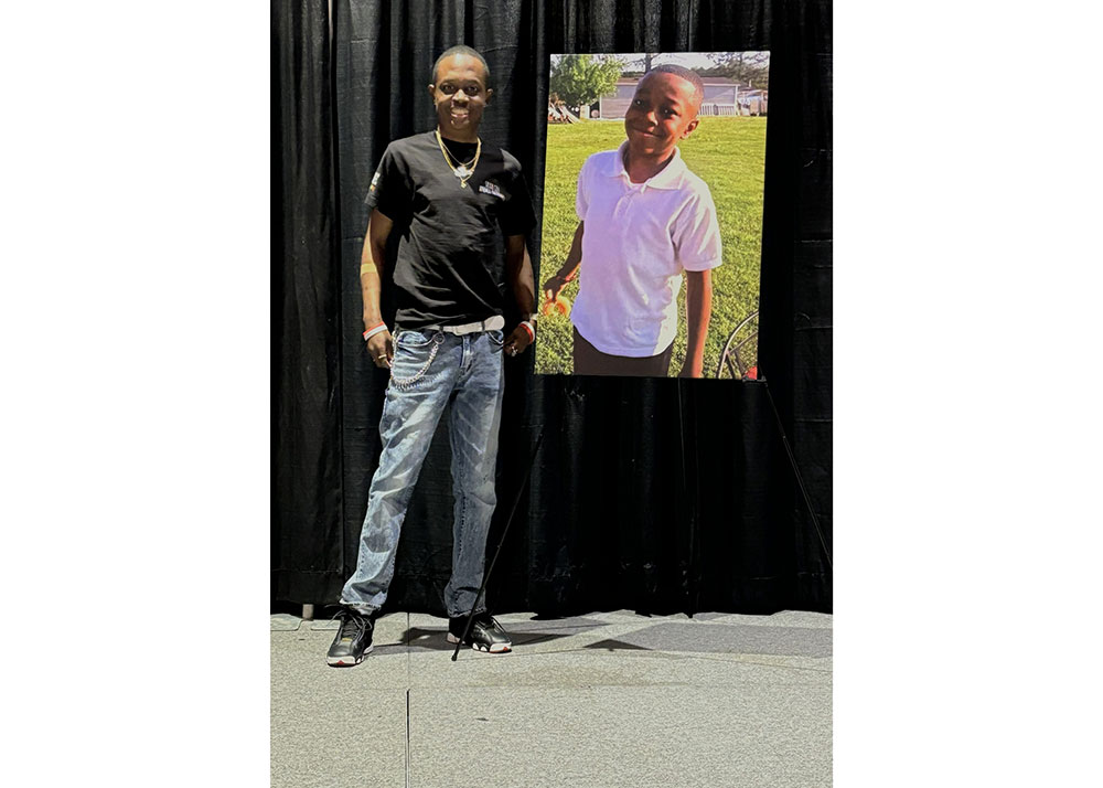 Travis Robinson stands beside a photo of his younger brother.