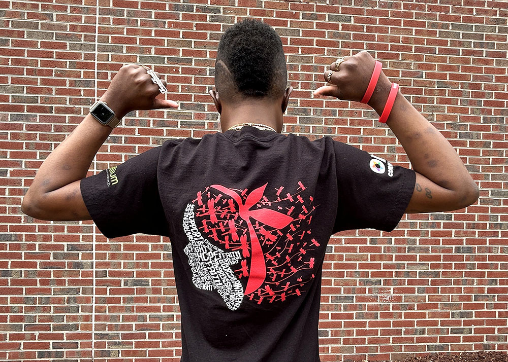 Travis Robinson facing backwards and pointing with both hands to the back of his shirt.