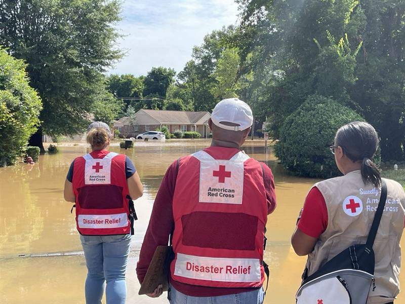 Red Cross volunteers looking at a flooded road.