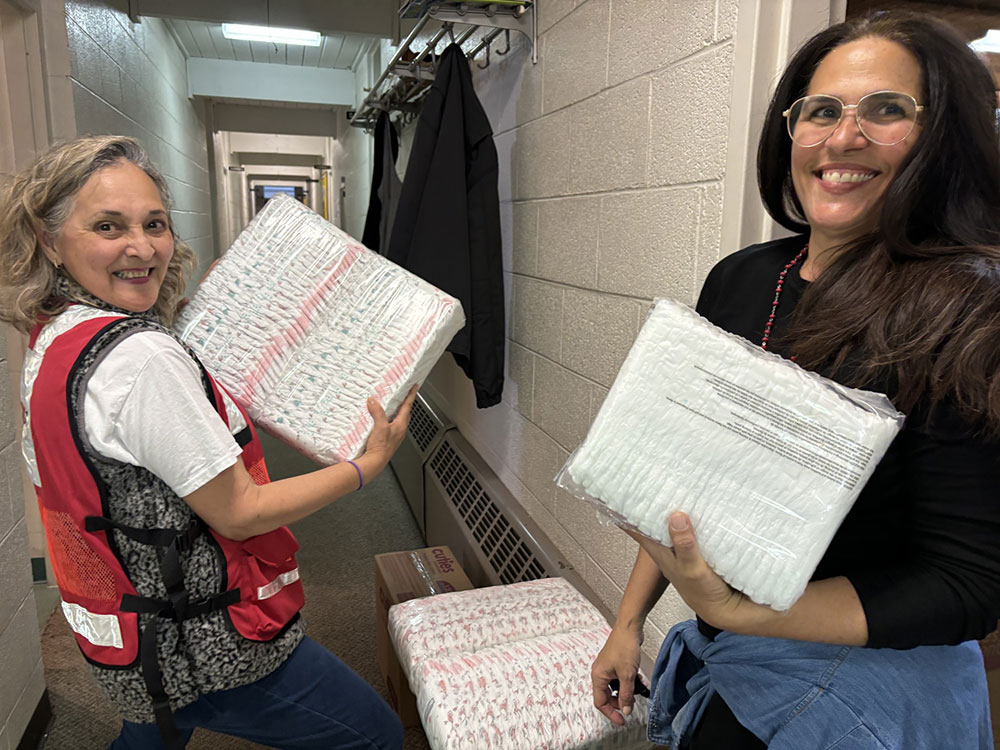 red cross volunteers holding packaged diapers.