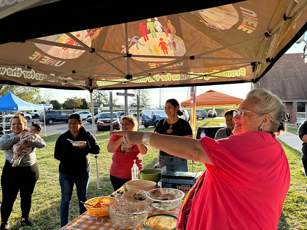 group of people under a canopy being served food.