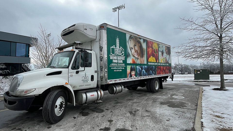 large box truck next to a building on a snowy road.