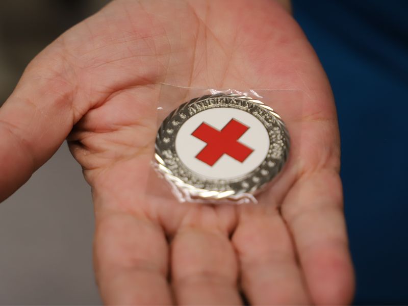 someone holding red cross coin