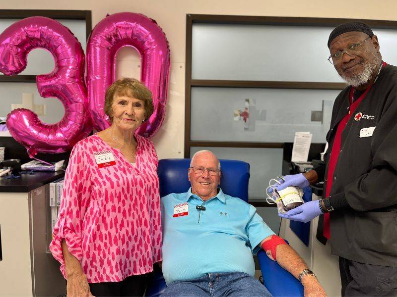 Married blood donors Max and Judy Whitley stand beside CLT phlebotomist Gary