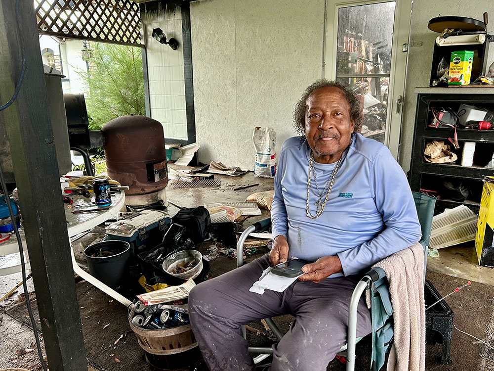Calvin Lewis sitting in chair and holding a smartphone.