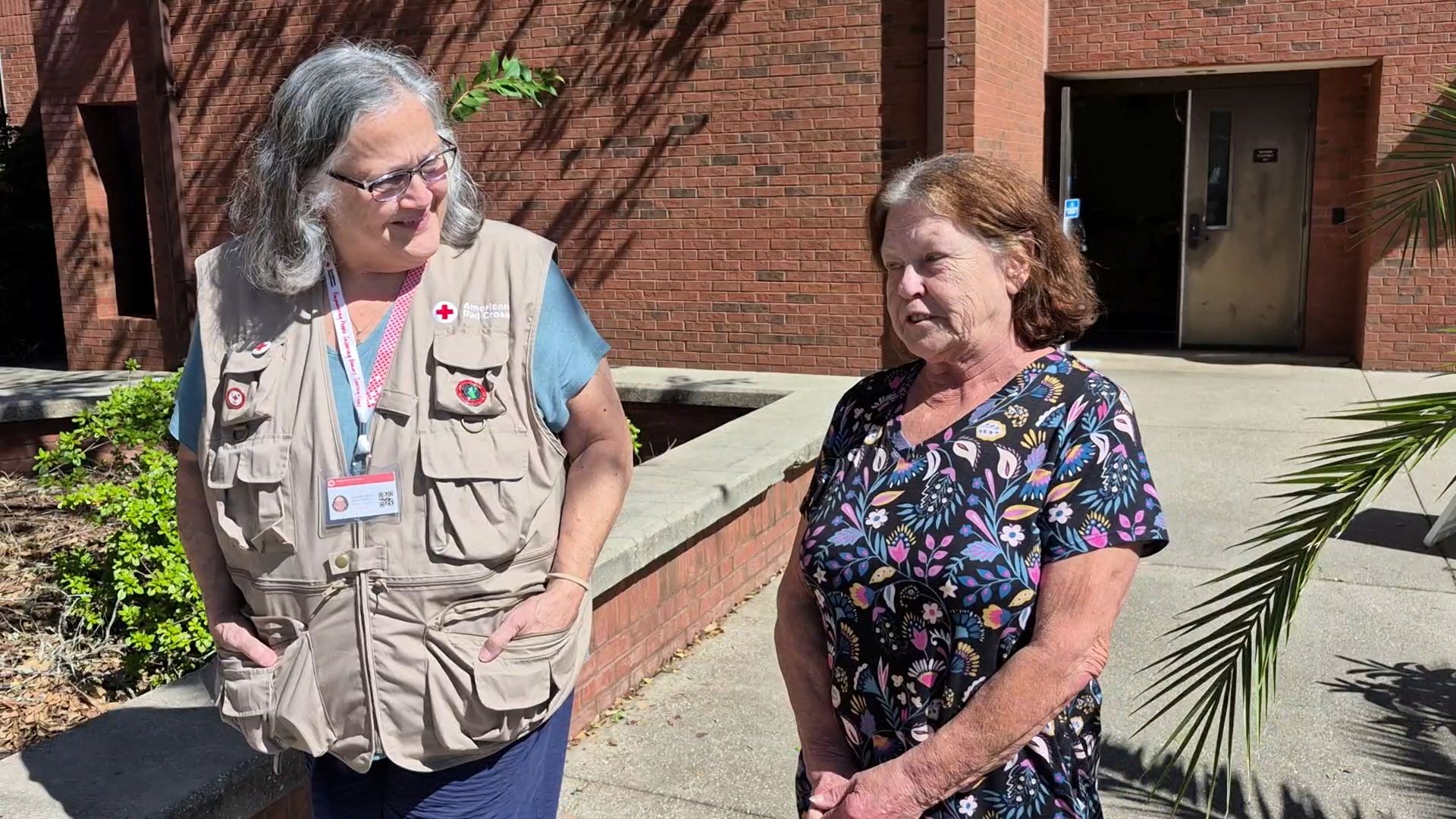 volunteer speaking with woman outside of building