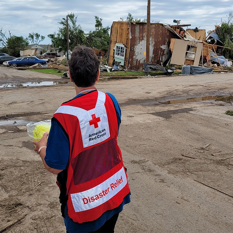 Red Cross volunteer looking at destroyed home