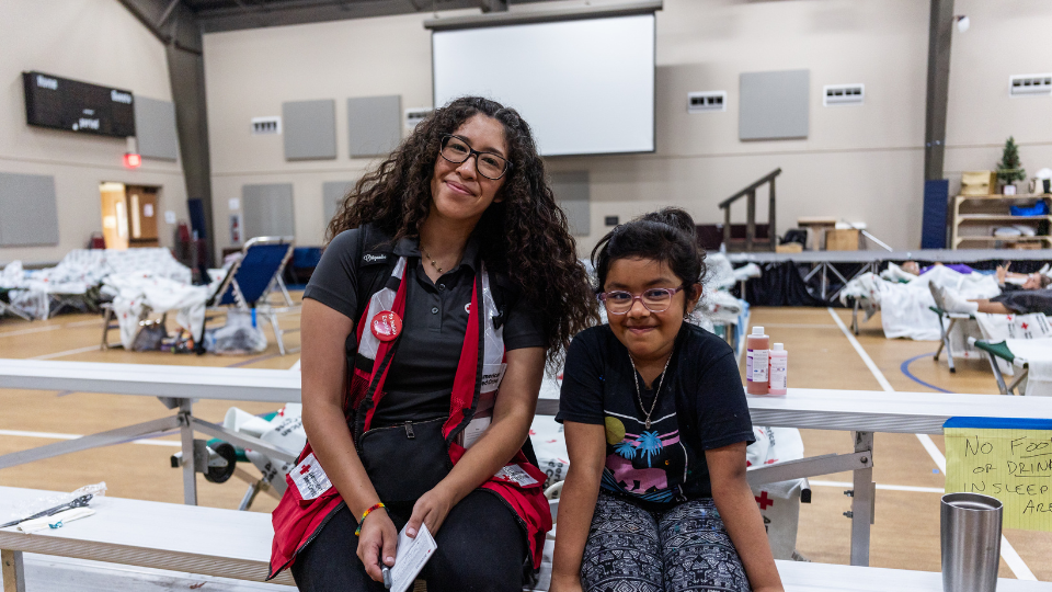 red crosser in shelter with young child.